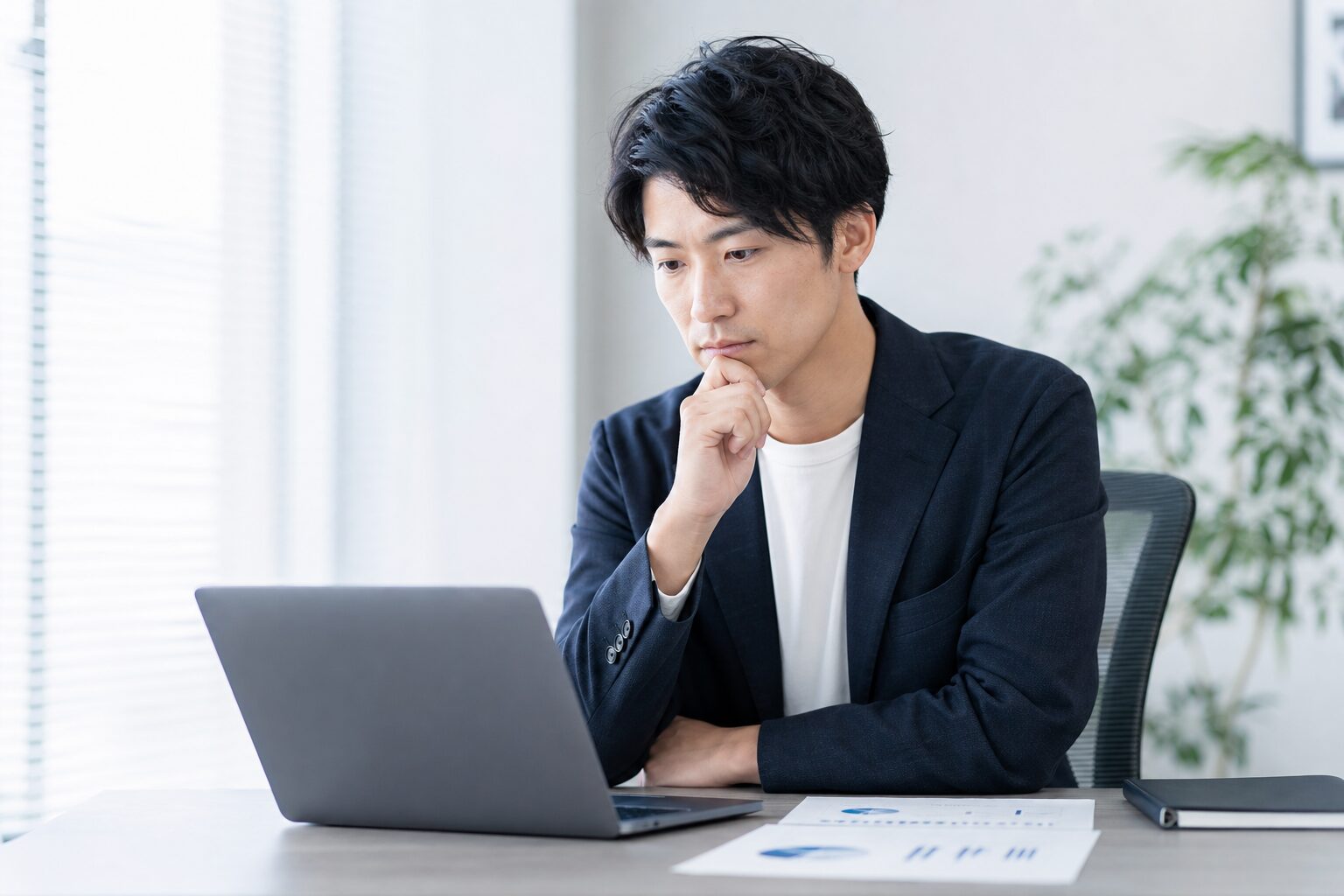 オフィスでパソコンを見ながら考えている風景画像